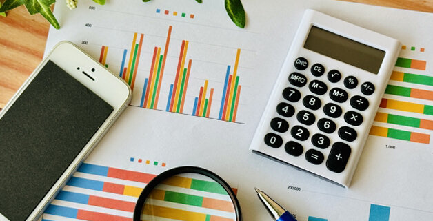 机の上に、スマホ、計算機、調査書類。