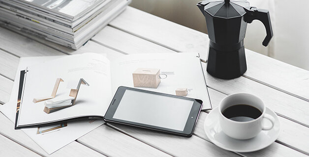 テーブルにギフトカタログとタブレットとコーヒーがある写真